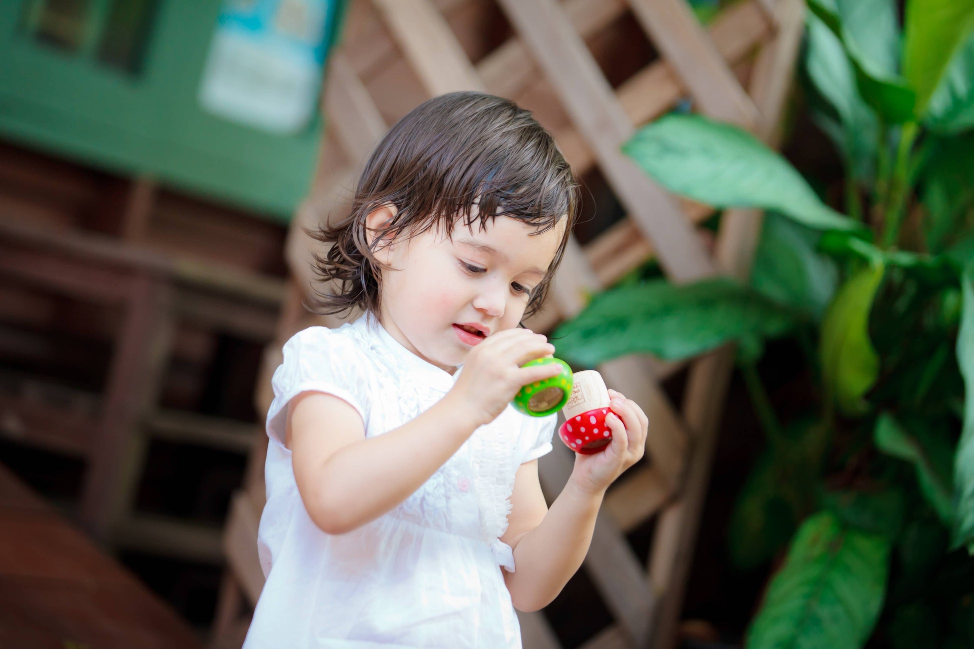 A young child exploring a PlanToys Mushroom Kaleidoscope toy outside, enhancing their creative thinking skills.