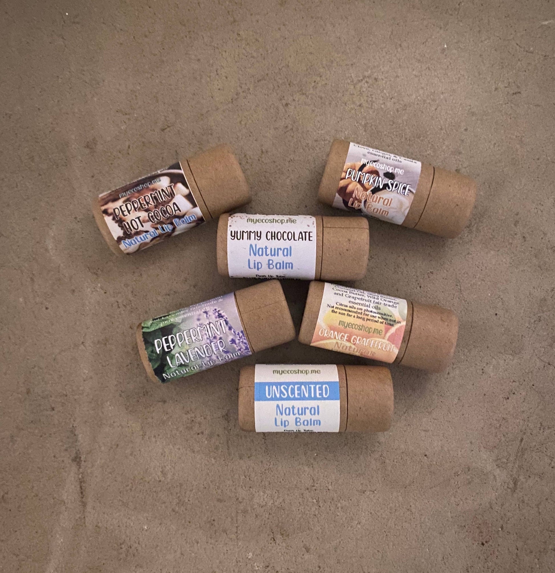 Variety of natural lip balms neatly laying on ground.