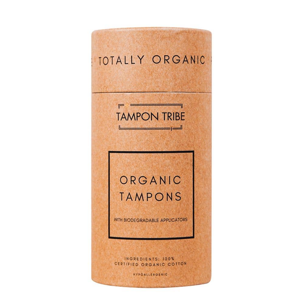 A cylindrical package labeled "Tampon Tribe organic tampons" with biodegradable, plastic-free applicators, indicating the product is made from certified organic cotton.