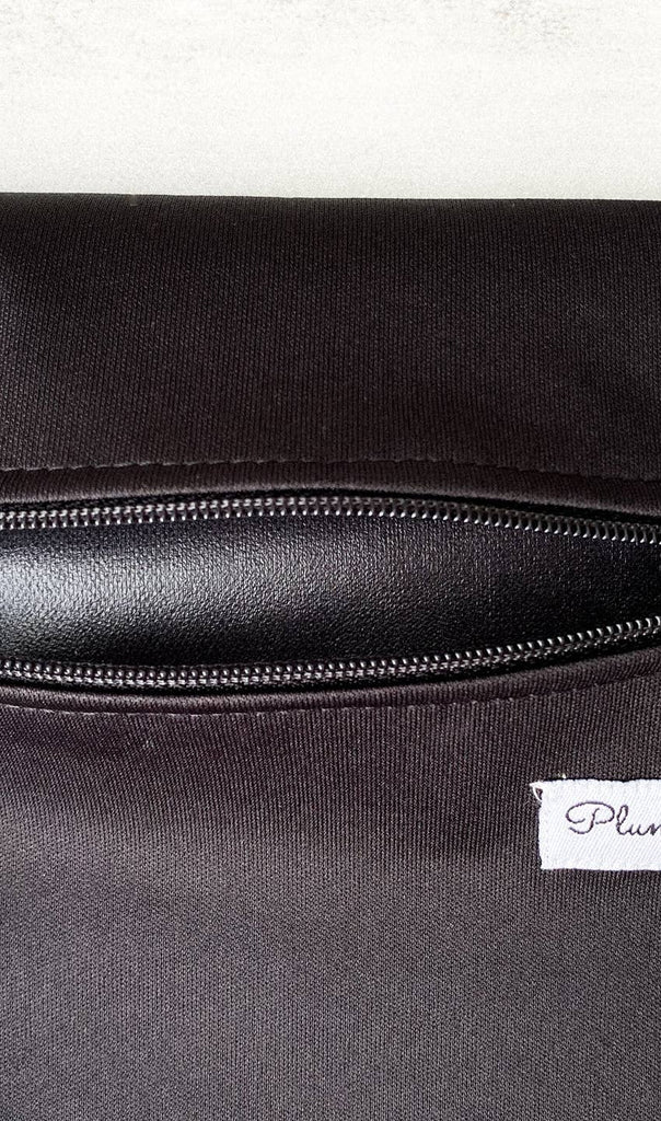 Close-up of a black waterproof Plum Thyme Medium Wet Bag with a zipper and a label that reads "pure", perfect for reusable period pads.