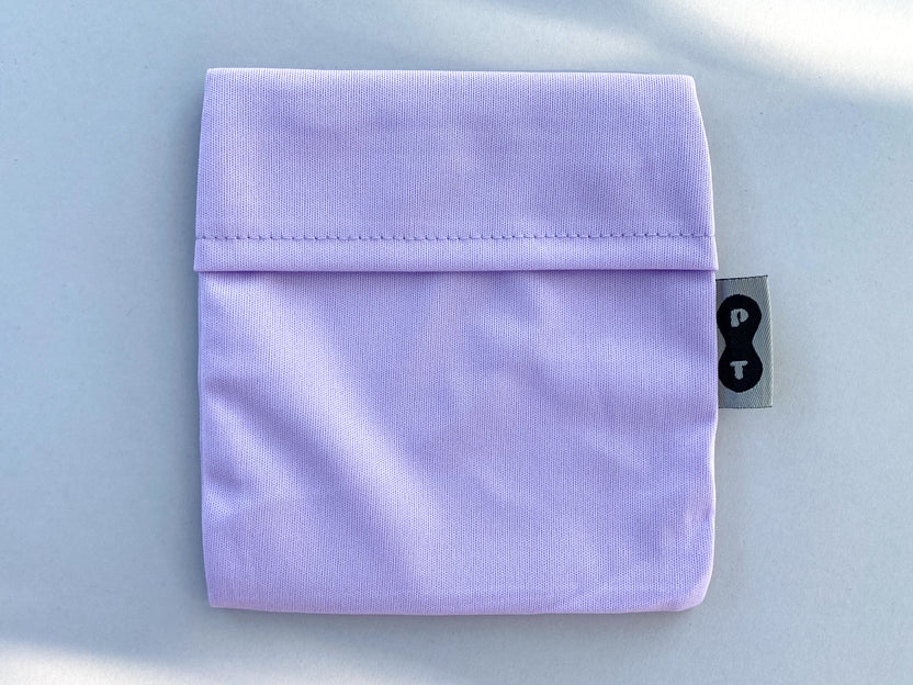 A folded Plum Thyme Pad Wrapper with a black tag featuring a white lock symbol on a light background.