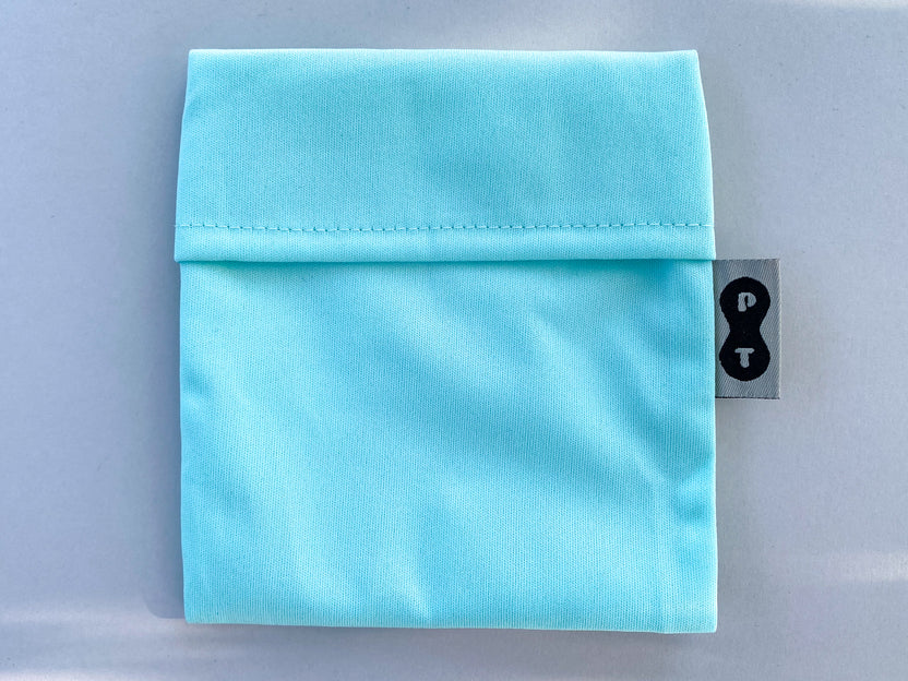 A folded light blue Plum Thyme Pad Wrapper with a clothing tag on the right side.
