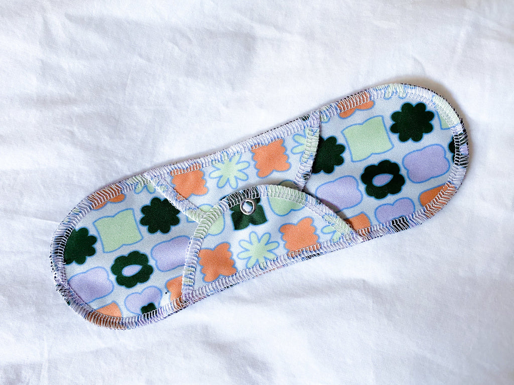 A floral-patterned Plum Thyme Moderate- Organic Reusable Menstrual Cloth Period Pad made from organic cotton on a white background.