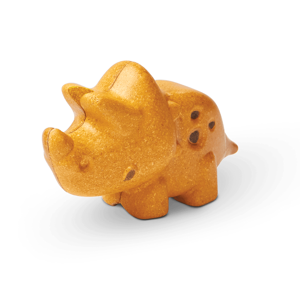A sustainable PlanToys Triceratops shaped like a cookie on a green background with its shadow visible.